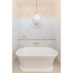 a white bath tub sitting under a light fixture