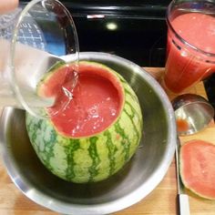 watermelon being poured into a metal bowl with spoons and utensils