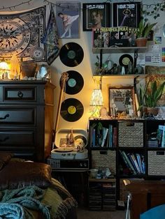 a room filled with lots of records and pictures on the wall above a chest of drawers