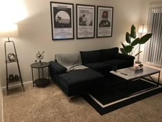 a living room with two posters on the wall and a black couch in front of it