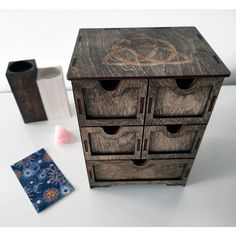 a wooden cabinet with drawers next to a vase and napkin holder on a white table