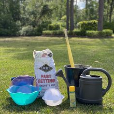 gardening supplies sitting in the grass near a watering can, shovel, and potted planter