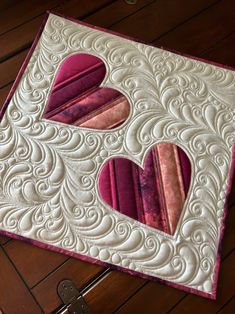 a close up of a piece of fabric on a table with a heart shaped applique