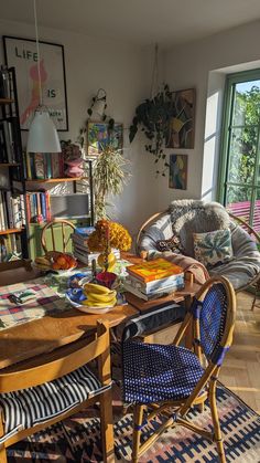 a living room filled with furniture next to a window covered in lots of books and plants