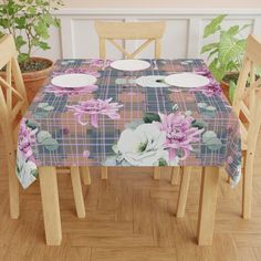 the table cloth has flowers on it and is next to two chairs with plates on them