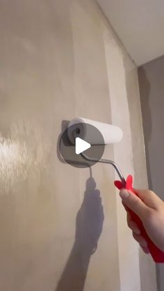 a person using a paint roller on a wall with the shadow of a hand holding a brush