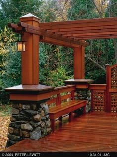 a wooden bench sitting on top of a wooden deck next to a stone and wood structure