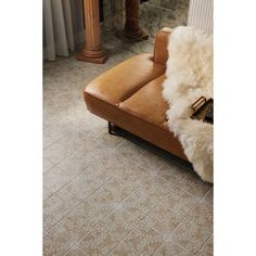 a brown leather couch sitting on top of a tiled floor