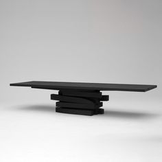 a black table sitting on top of a white floor next to a gray wall in the background