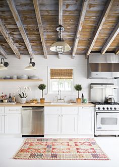 a kitchen with white cabinets and wood beams on the ceiling is featured in an instagram