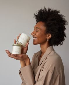 a woman holding a jar of candles in one hand and smiling at the other with her mouth open