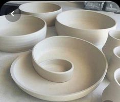 many white bowls and plates are stacked on top of each other