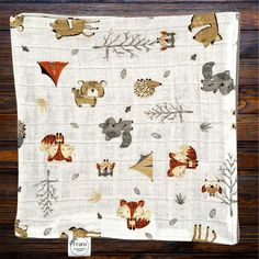 an image of a baby blanket with animals on it and leaves in the back ground