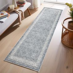 a living room with a large rug on the floor and a plant in front of it