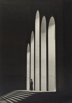 the shadow of a person standing in front of a wall with arches and columns on it