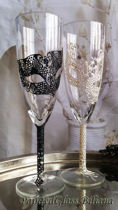 two wine glasses sitting on top of a table next to each other, one is decorated with black and white lace