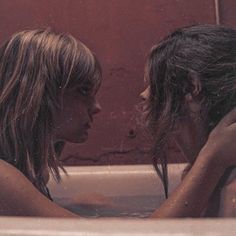 two women in a bathtub with their heads together