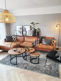 a living room with couches, tables and pictures on the wall above them in front of a large window