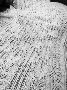 a white crocheted blanket sitting on top of a bed