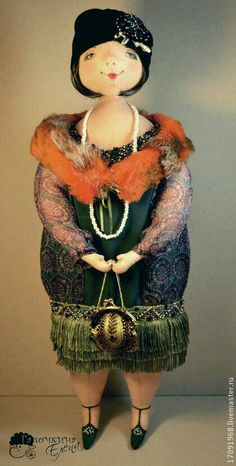 a doll is dressed in a green dress and red fur stoler, holding a purse