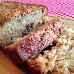 a loaf of bread sitting on top of a wooden cutting board next to a slice of cake