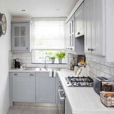 a kitchen with white and gray cabinets, an oven, sink and radiator