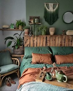 a bed with green sheets and pillows in a room filled with potted plants on top of it