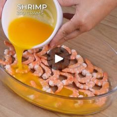 someone pouring orange juice into a bowl filled with shrimp