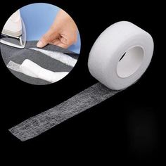 a roll of white tape with a hand on it and an ironing board in the background