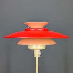 a red lamp sitting on top of a table next to a gray wall and floor