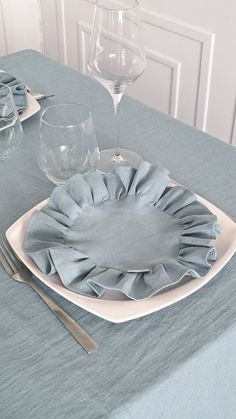 a blue table cloth with ruffled edges and silverware sits on a white plate