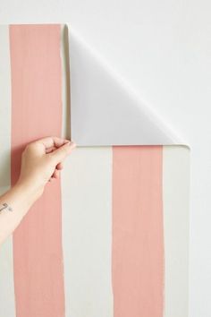 a person is painting a wall with pink and white stripes