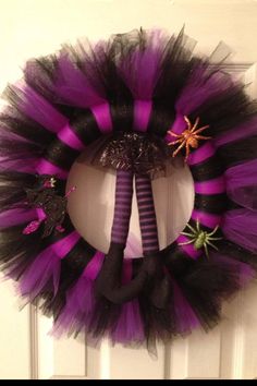 a purple and black halloween wreath hanging on a door