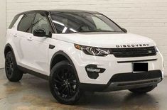 a white land rover is parked in a room with a brick wall and black rims