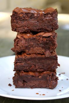 a stack of brownies sitting on top of a white plate next to each other