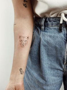 a woman's arm with a small tattoo of a tiger on the left wrist