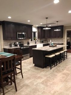 a large kitchen with dark wood cabinets and marble counter tops