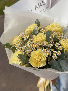 a person holding a bouquet of yellow flowers