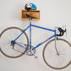 a blue bike with a helmet on the back rack and a wooden shelf above it