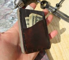 a hand holding a wallet with money in it next to a pair of pliers