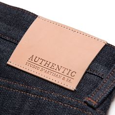 an authentic label is on the back of a pair of blue denim jeans with brown stitching