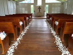 the aisle is decorated with white flowers and petals on each side, along with wooden pews