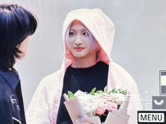 a man in a pink hoodie holding flowers next to a woman with black hair