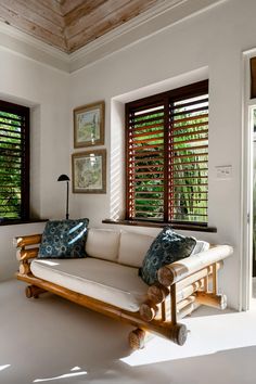 a living room filled with furniture and windows covered in wooden shutters, next to a white couch