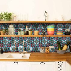 a kitchen with colorful tiles on the wall and wooden counter tops, along with white cabinets