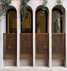 three windows with wooden screens and ivy growing on them