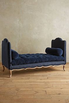 a blue chaise lounge sitting on top of a hard wood floor next to a wall