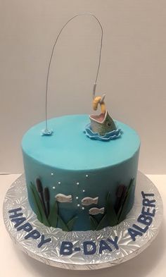 a blue birthday cake with a fishing theme on the front and bottom, sitting on top of a silver plate