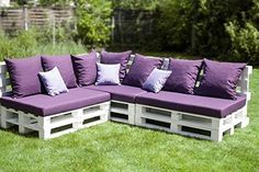 a couch made out of wooden pallets with purple pillows on it in the grass