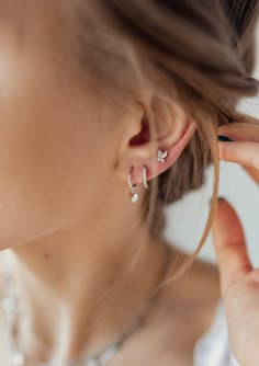 This is a set of 3 different, yet complementary earrings, all made from 925 sterling silver. It includes: ✅ 1 huggie earring with a small, solid, heart-shaped pendant attached to its lower edge, ✅ 1 huggie earring with 9 tiny clear-coloured zirconia stones set into its outer rim, and ✅ 1 tiny butterfly-shaped stud earring featuring 2 Marquise-shaped, clear-coloured zircon stones set above 2 small round, clear-coloured zircon stones. Subtle, elegant, and versatile, this set is an easy way to upda Huggie Earrings Silver, Huggie Earring, Stacked Earrings, Butterfly Earrings Stud, Butterfly Earrings, Ear Jewelry, Huggies Earrings, Stud Earring, Silver Hoop Earrings